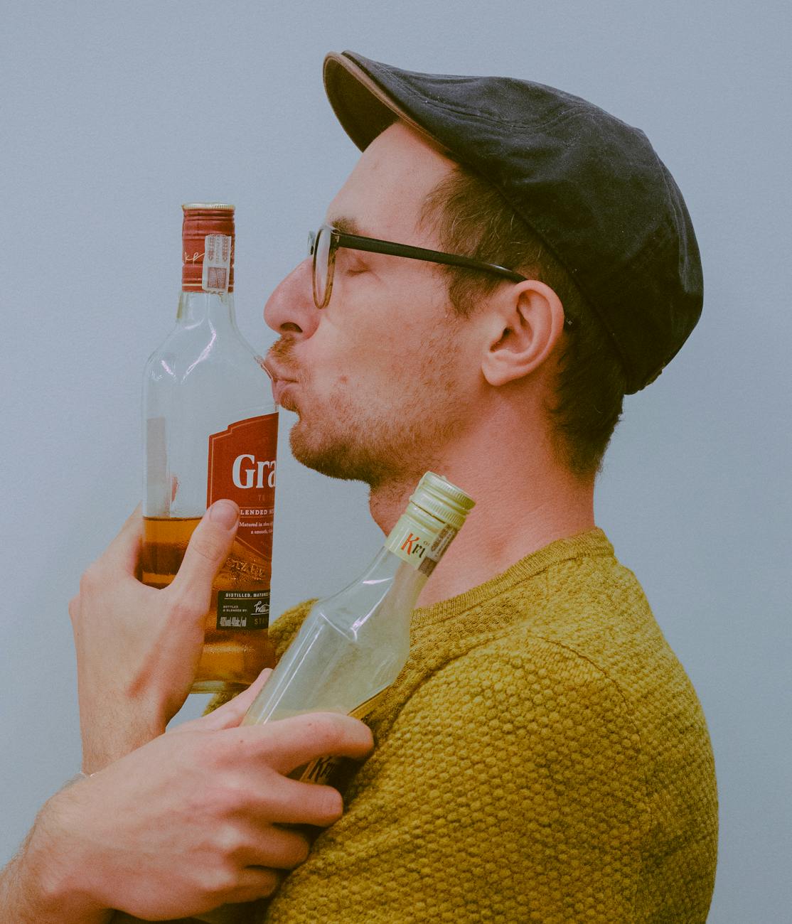 a man in yellow sweater holding a bottle