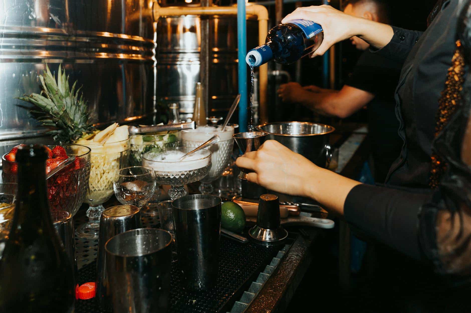 person pouring wine in a jigger making a cocktail drink