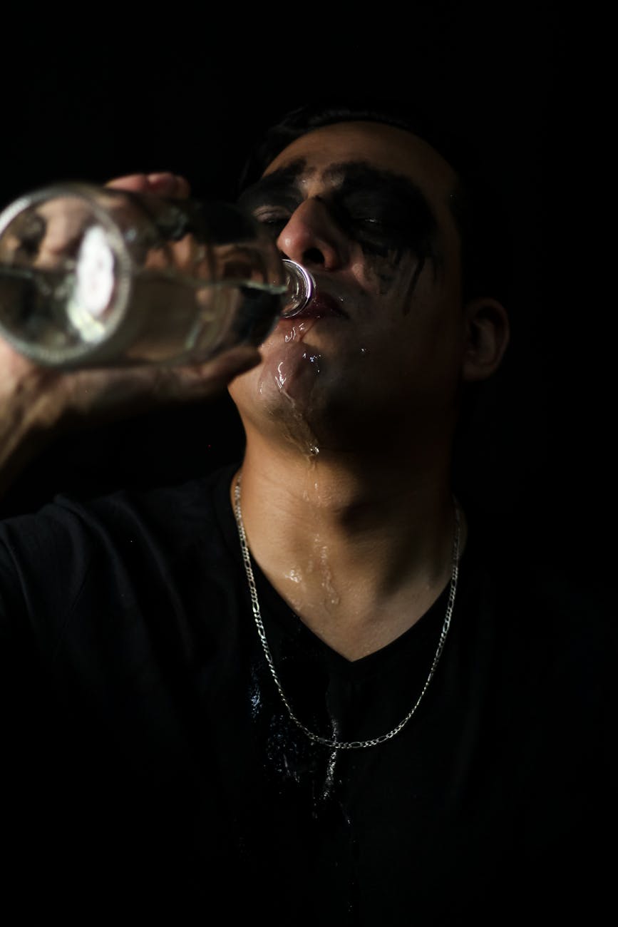 a man with black makeup drinking from a bottle