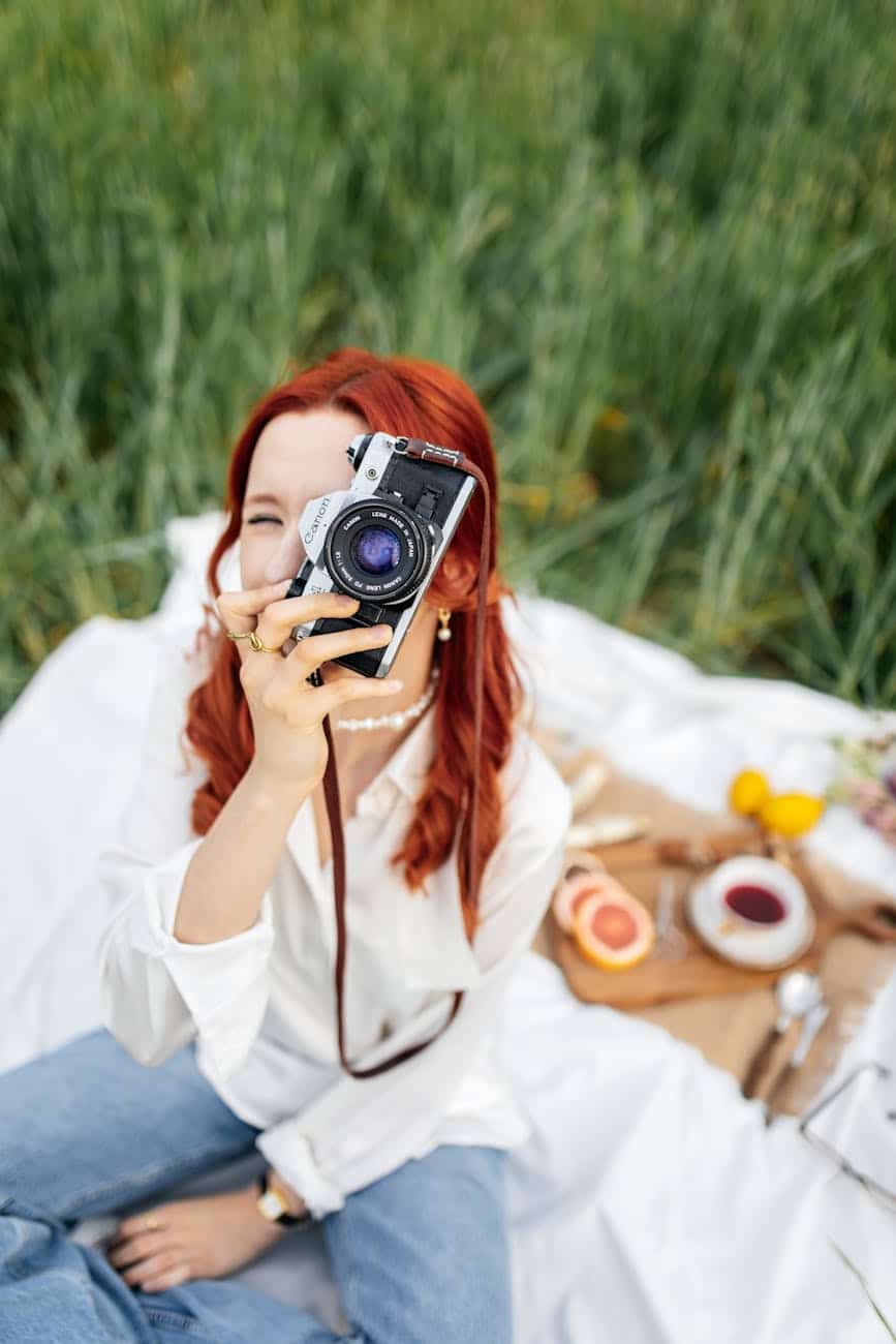 woman in shirt sitting with camera on picnic social media addiction detox rehab