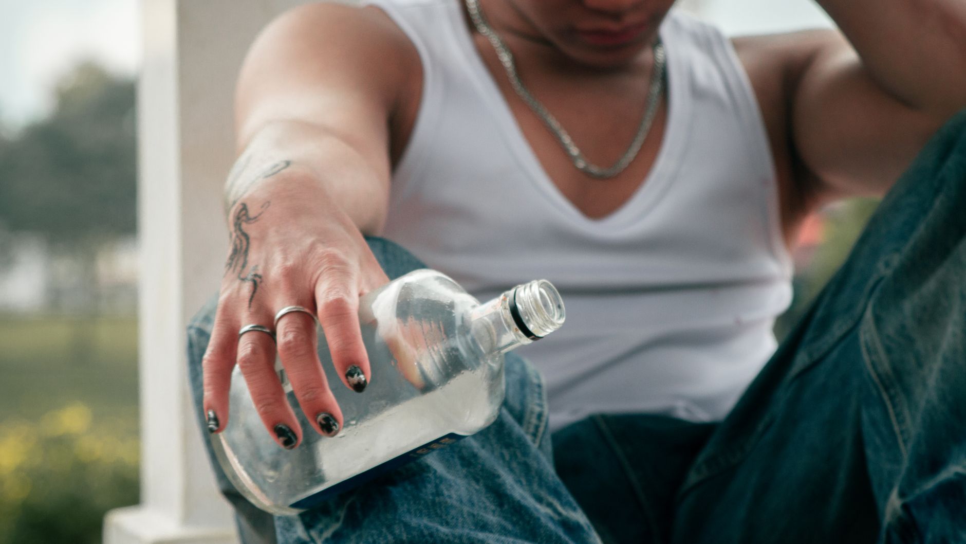 young man holding an empty bottle outdoors Addiction withdrawal symptoms explained