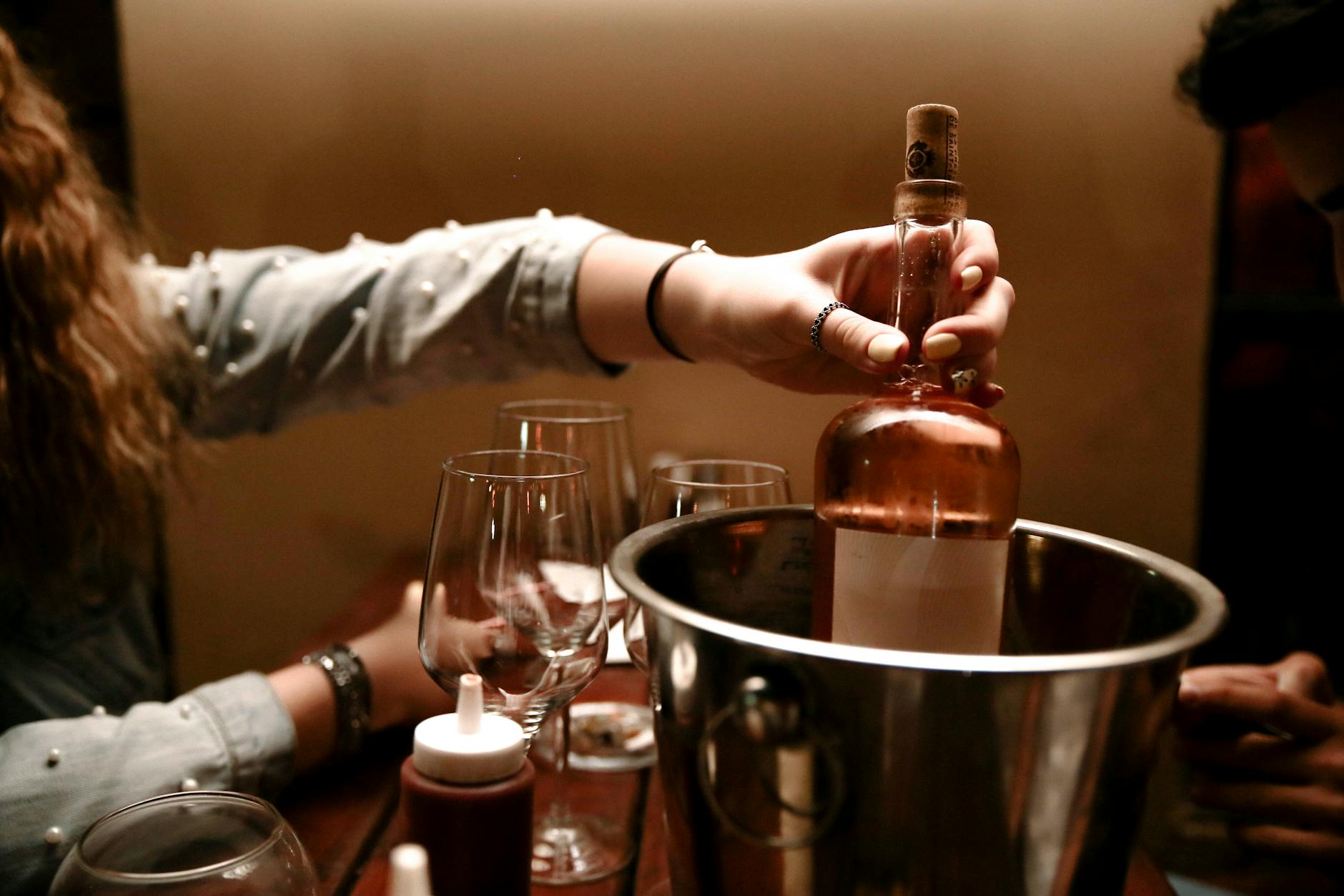 person holding a wine bottle on stainless ice bucket