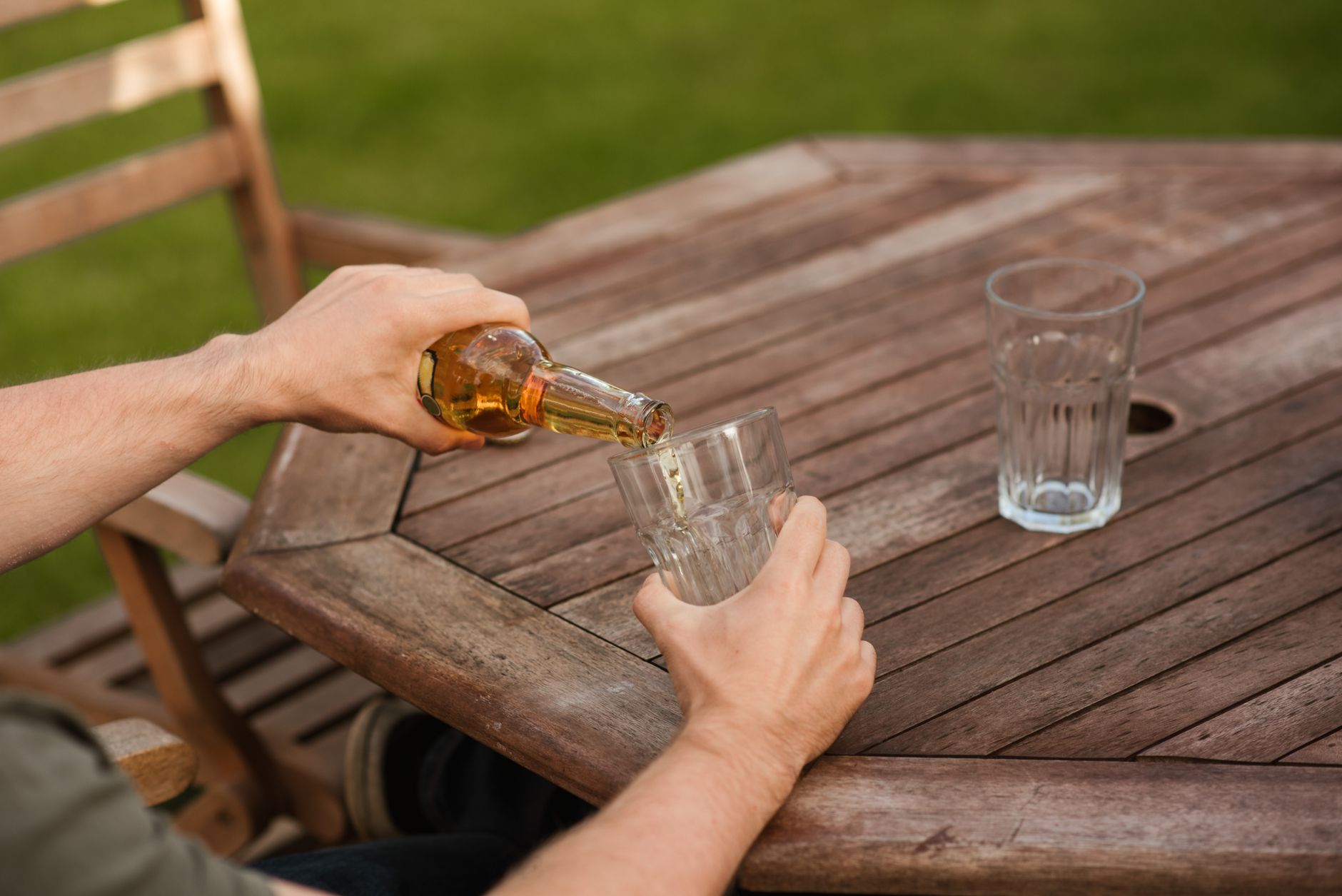 man pouring beer from bottle into glass mug home detox