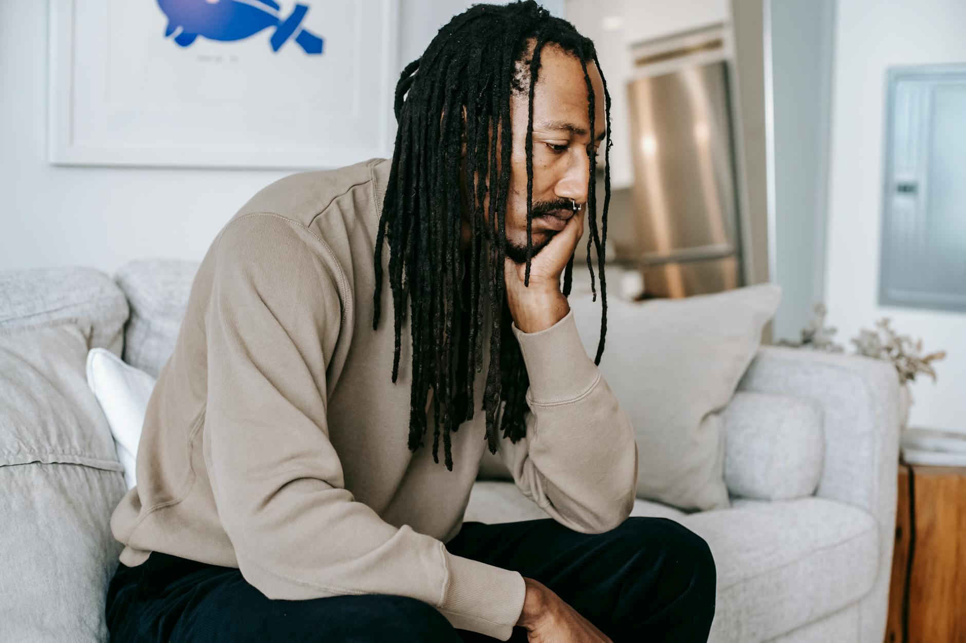 sad black man sitting on sofa a syringe with brown chemical on a wooden table