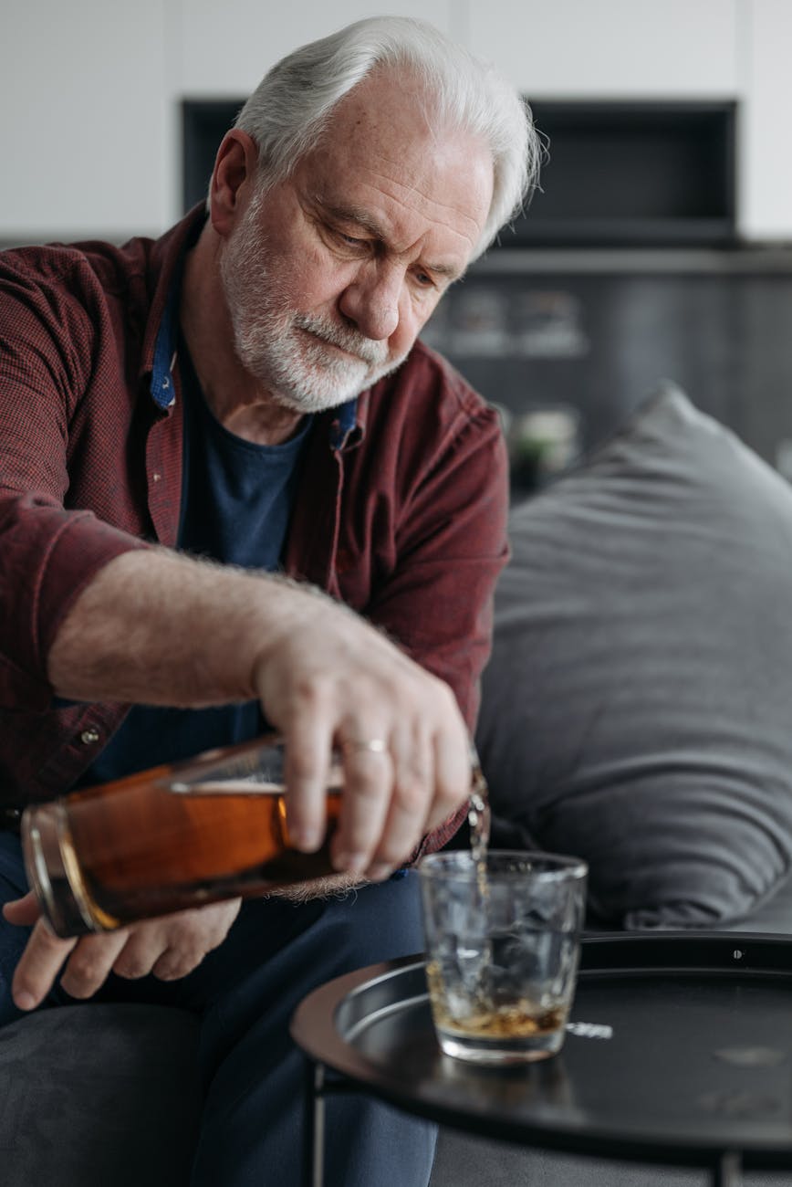 a man with gray hair pouring a drink into a glass. Exploring SMART recovery for alcohol addiction