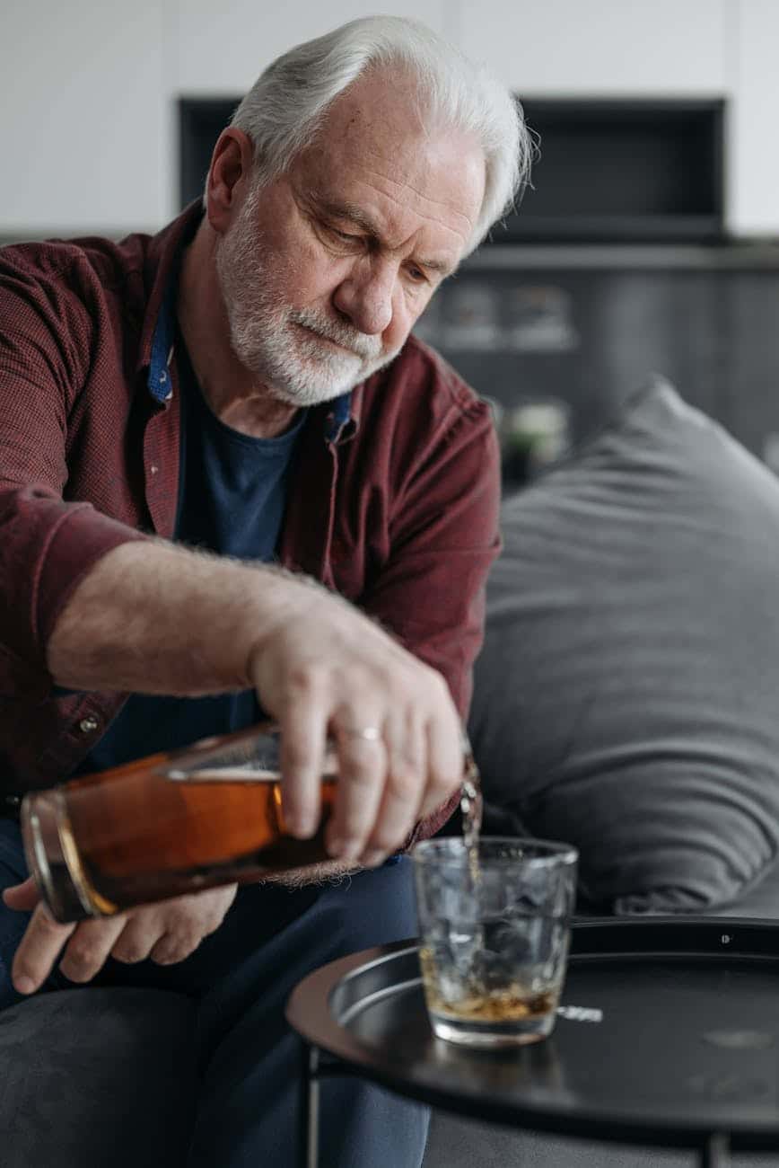 a man with gray hair pouring a drink into a glass