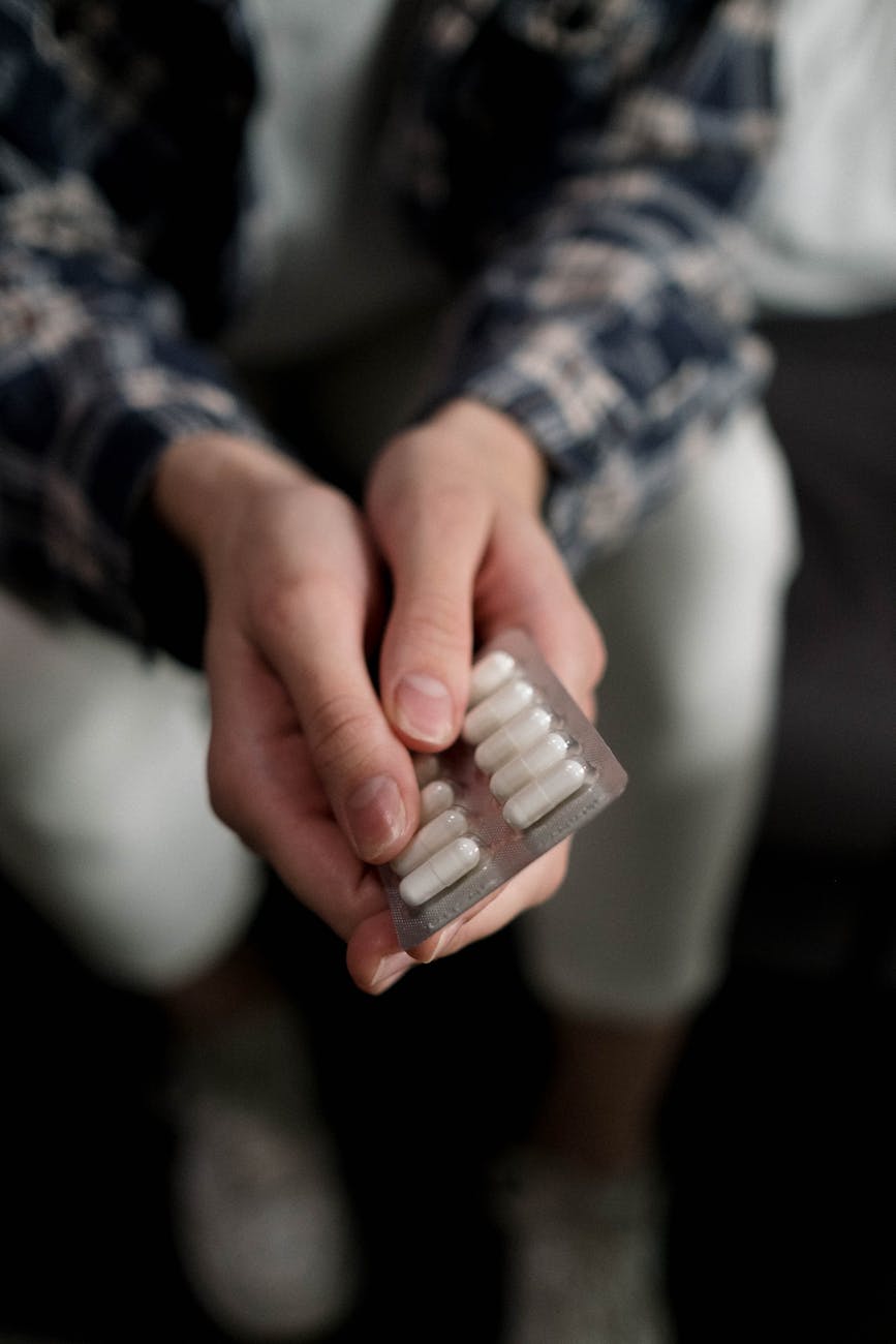 person holding white medicine capsules https://findmearehab.net/contact-support/